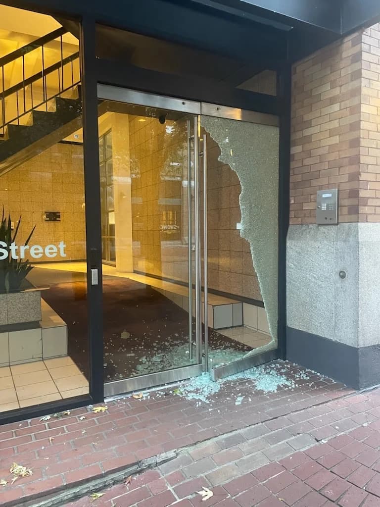Vancouver commercial entrance with shattered side-panel glass and debris before emergency board-up