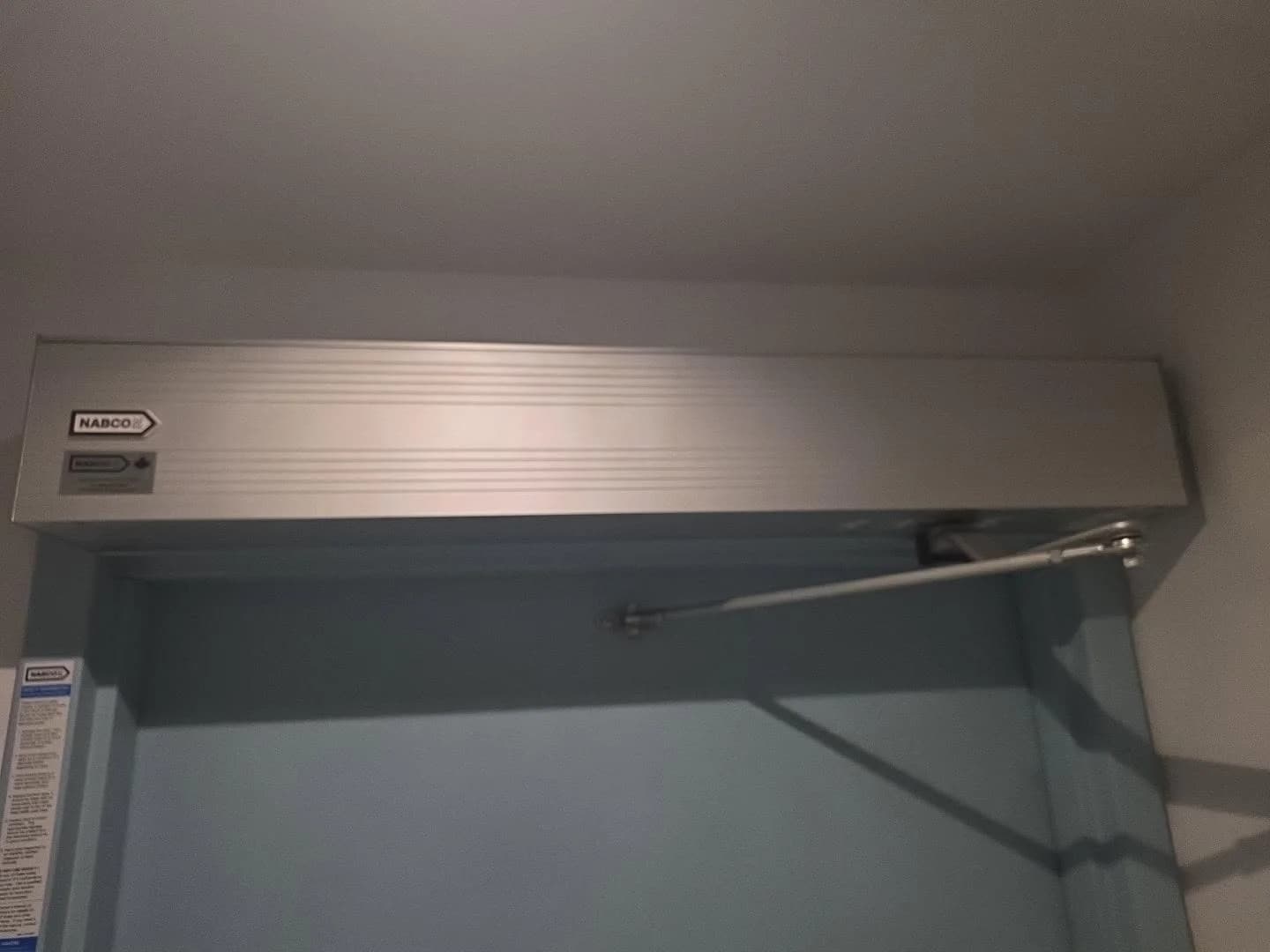 Automatic swing-door operator and arm mounted above a commercial door
